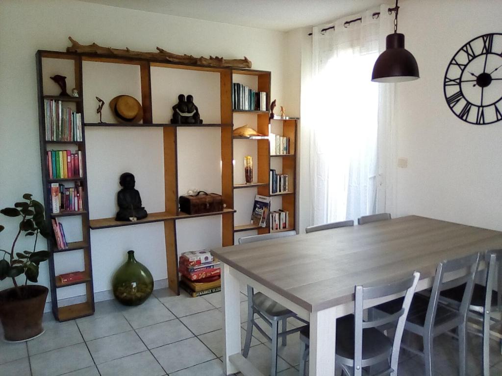 Maison Gruissan Mateille في جرويسان: غرفة طعام مع طاولة وساعة على الحائط