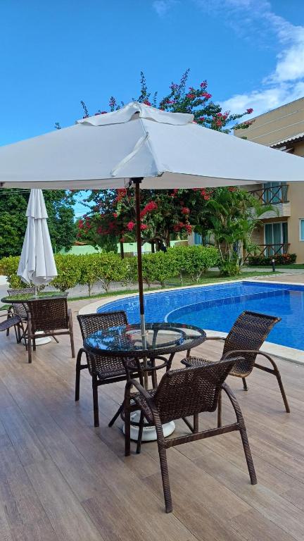 a table and chairs with an umbrella next to a pool at LAZER EM GUARAJUBA in Guarajuba