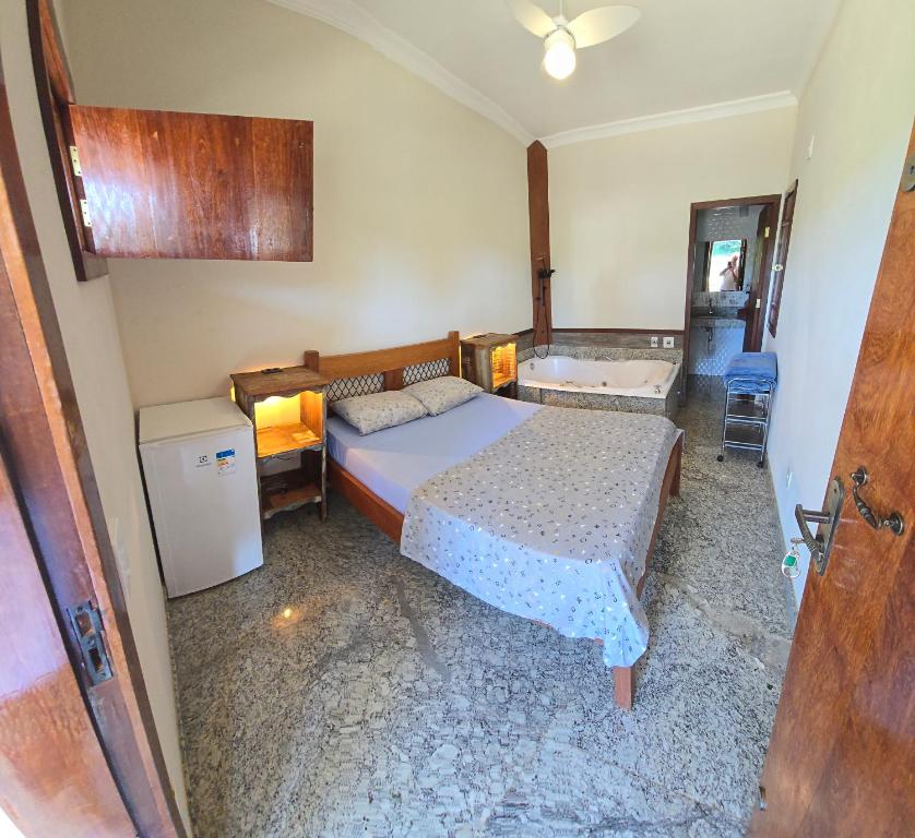 Fazenda do Prata Ecoresort في Caratinga: غرفة نوم فيها سرير وحوض استحمام