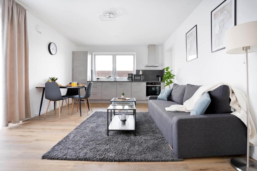 uma sala de estar com um sofá cinzento e uma mesa em Moderne Apartments im Herzen von Osnabrück I private Tiefgarage I home2share em Osnabrück