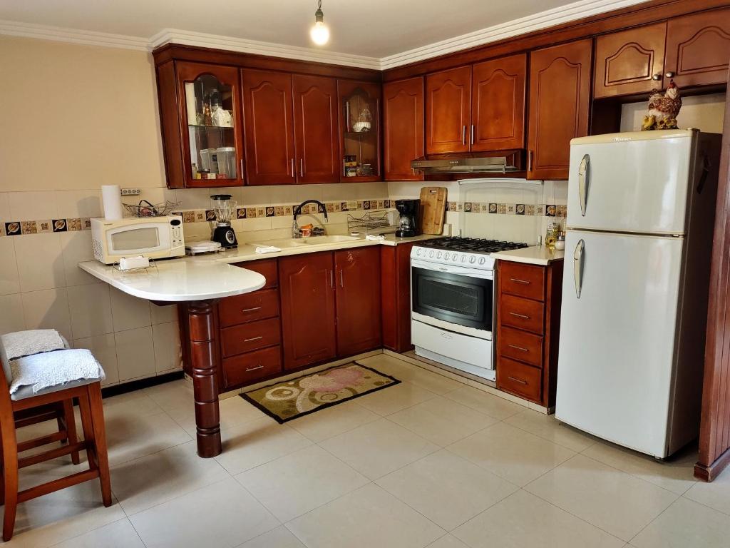 a kitchen with wooden cabinets and a white refrigerator at Casa Quirola hermosa y muy grande in Cuenca