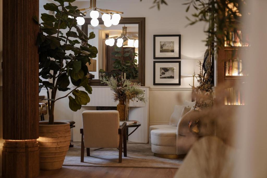 ein Wohnzimmer mit einem Tisch, Stühlen und einem Spiegel in der Unterkunft Hotel Pulitzer Paris in Paris