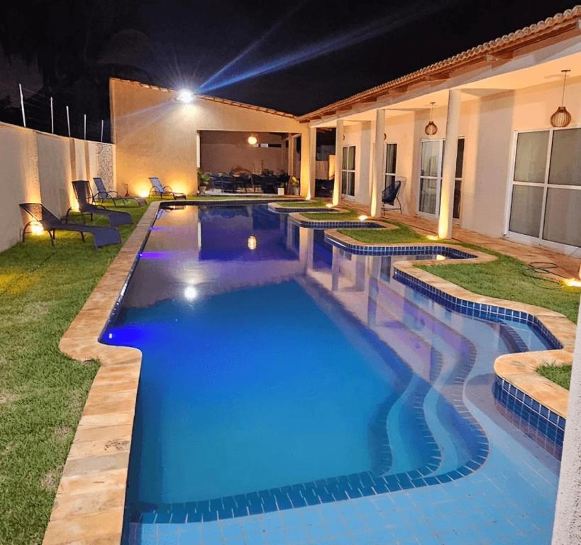 a swimming pool in a backyard at night at Chalés Mar e Sol in São Miguel do Gostoso