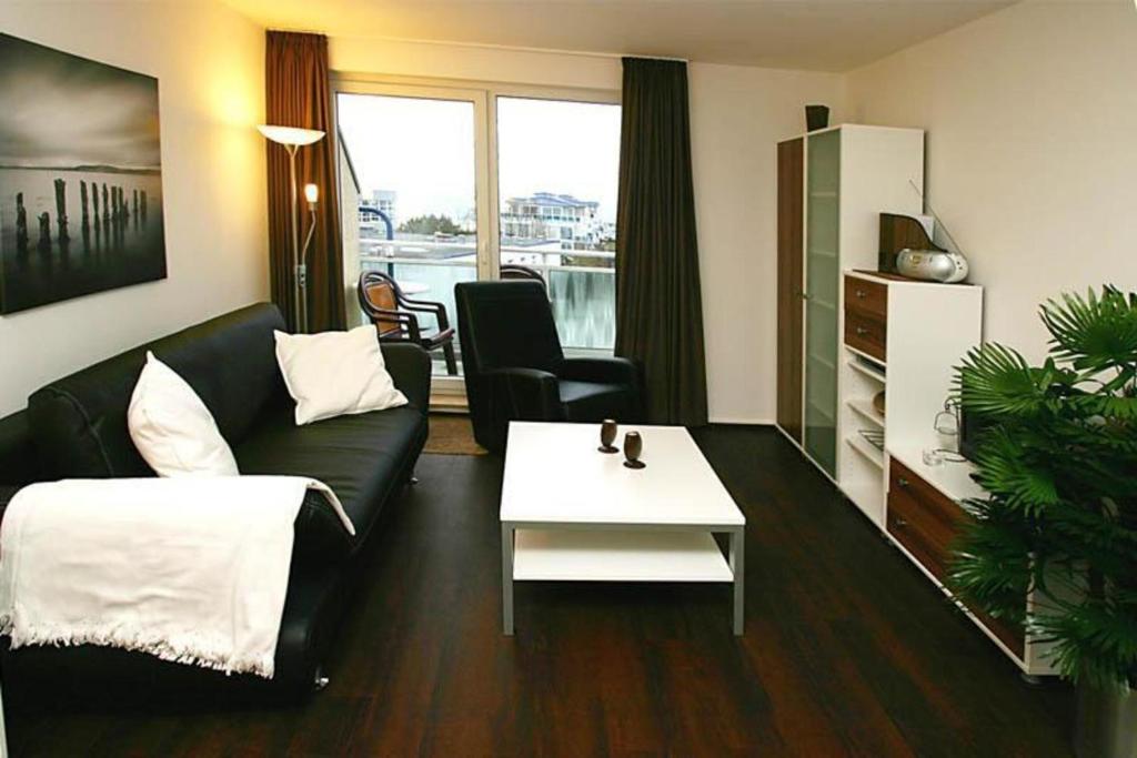 キュールングスボルンにあるYachthafenresidenz-Wohnung-8404-866のリビングルーム(黒いソファ、白いテーブル付)
