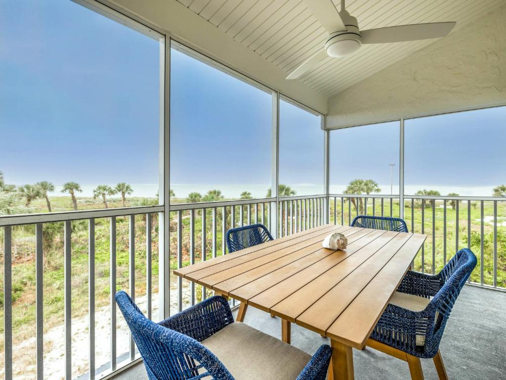 a wooden table and chairs on a balcony with windows at South Seas Resort - Official Site in Captiva