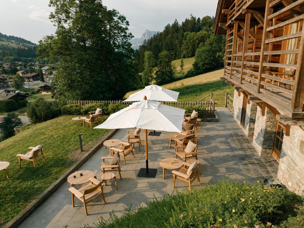 um pátio com mesas e cadeiras e um guarda-sol em Zannier Hotels Le Chalet em Megève