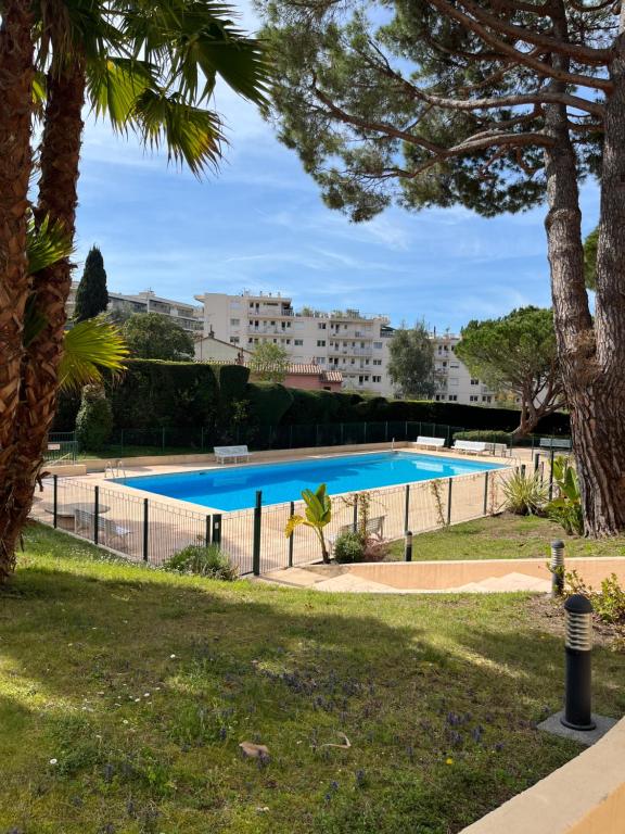 a swimming pool in a park with trees at Cosy Flat Cannes in Le Cannet