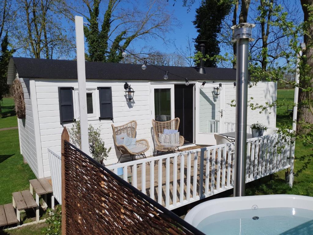 ein kleines weißes Haus mit einem Whirlpool auf einer Terrasse in der Unterkunft Pipowagen Warm Welkom in Wezep