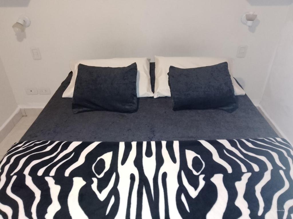 a bed with black and white sheets and two pillows at La Bendición in Campo Quijano