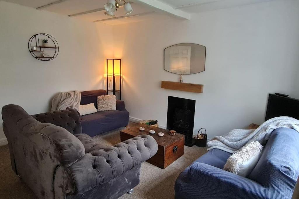 a living room with two couches and a fireplace at Shrigley cottage, quirky & quiet in Macclesfield