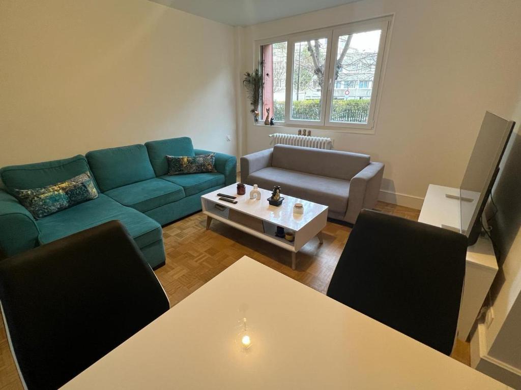 un salon avec un canapé bleu et une table dans l'établissement Appartement Chaleureux Portes de Paris, à Aubervilliers
