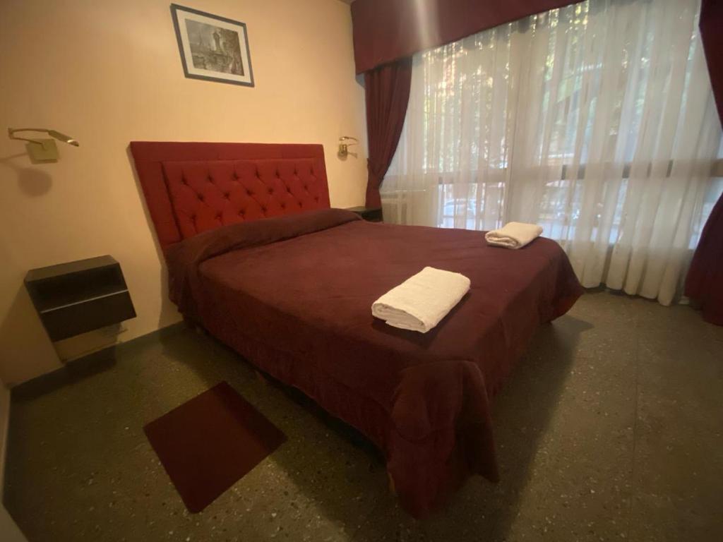 1 dormitorio con 1 cama roja y 2 toallas en Hermoso departamento en pleno microcentro en Mendoza