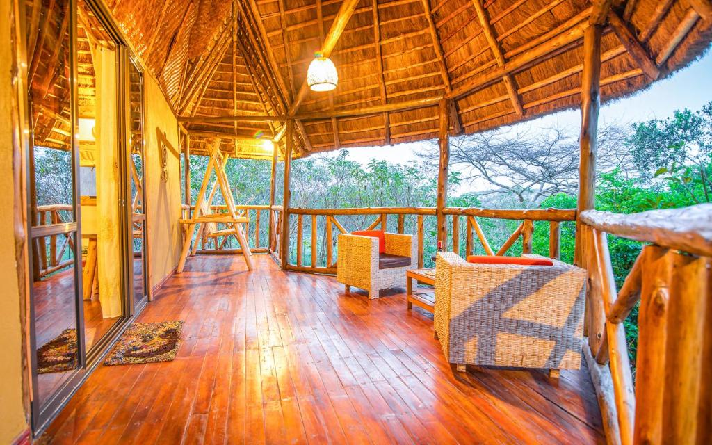 une terrasse couverte d'une maison revêtue de parquet dans l'établissement Embogo Safari Lodges, à Katoke