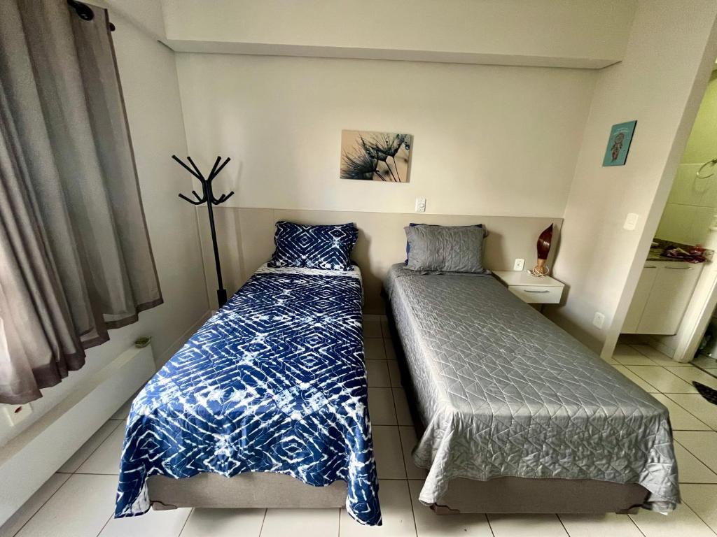 a bedroom with two beds and a night stand in it at Studio 909 - Iguatemi Ribeirão Preto in Ribeirão Preto