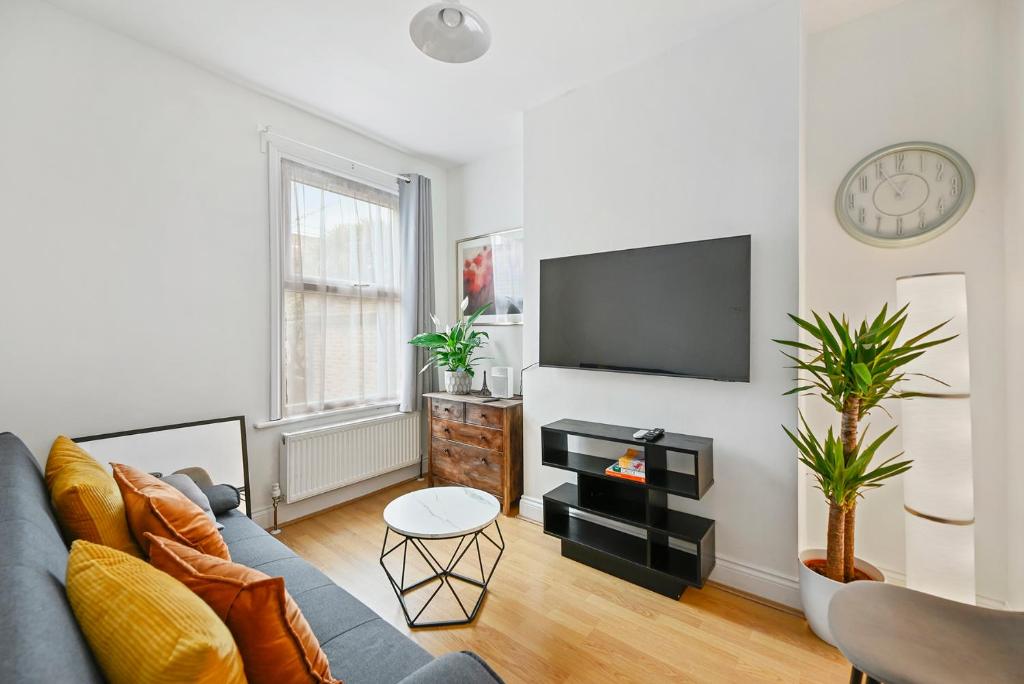 salon z niebieską kanapą i telewizorem z płaskim ekranem w obiekcie Cosy Urban Oasis 2 Bedroom Flat in Tottenham ( Sleeps 5 People ) w Londynie