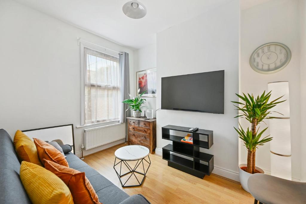 a living room with a blue couch and a flat screen tv at Cosy Urban Oasis 2 Bedroom Flat in Tottenham ( Sleeps 5 People ) in London