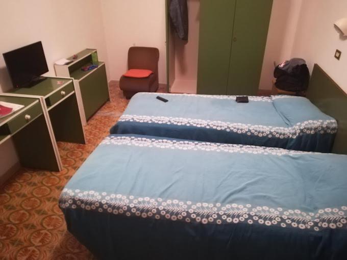 two beds in a room with a desk and a computer at hotel Plaza in Cesenatico