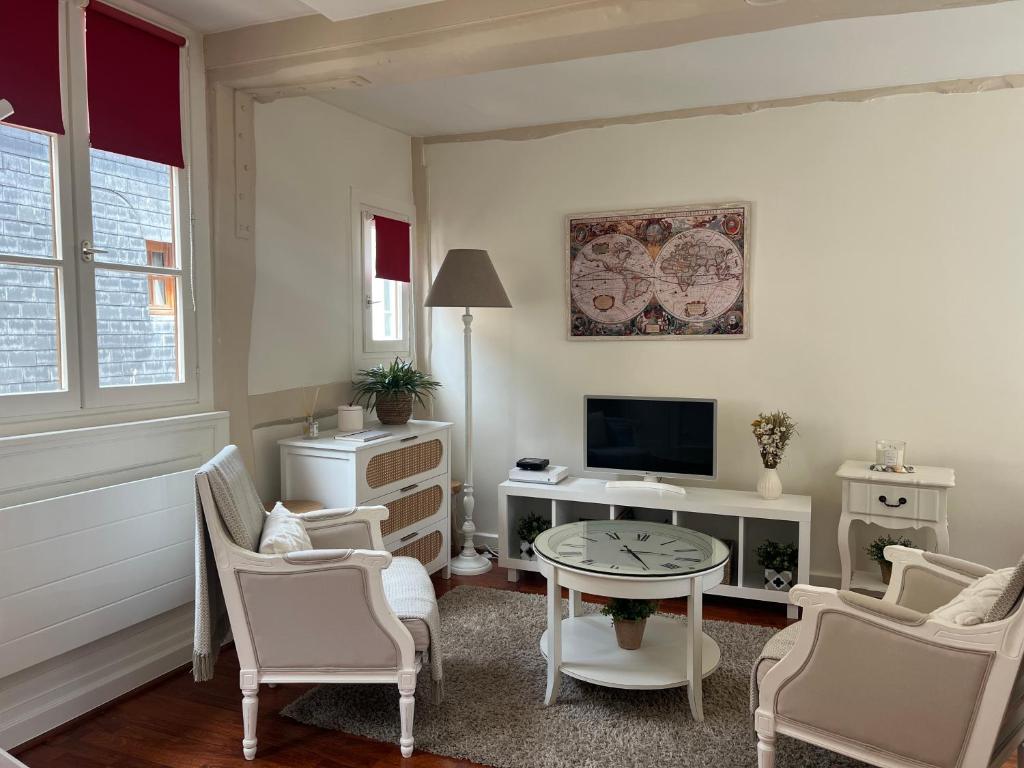 un salon avec une table, des chaises et une télévision dans l'établissement MISCANTHUS, à Honfleur