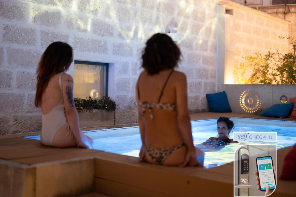 duas mulheres numa banheira de hidromassagem com um homem numa piscina em Vico Bianco Raro Villas Smart Rooms Collection em Ostuni