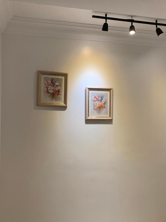 two framed paintings on a white wall with lights at cozy appartement meublé in Tangier