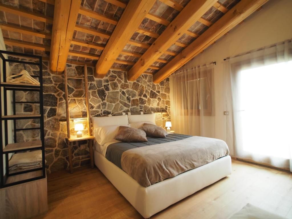 1 dormitorio con cama y pared de piedra en AZIENDA AGRICOLA CA' LUNGA, en Cinto Euganeo