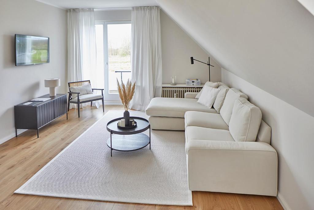 ein weißes Wohnzimmer mit einem weißen Sofa und einem Tisch in der Unterkunft Techts Landhus Birkenallee in Timmendorfer Strand