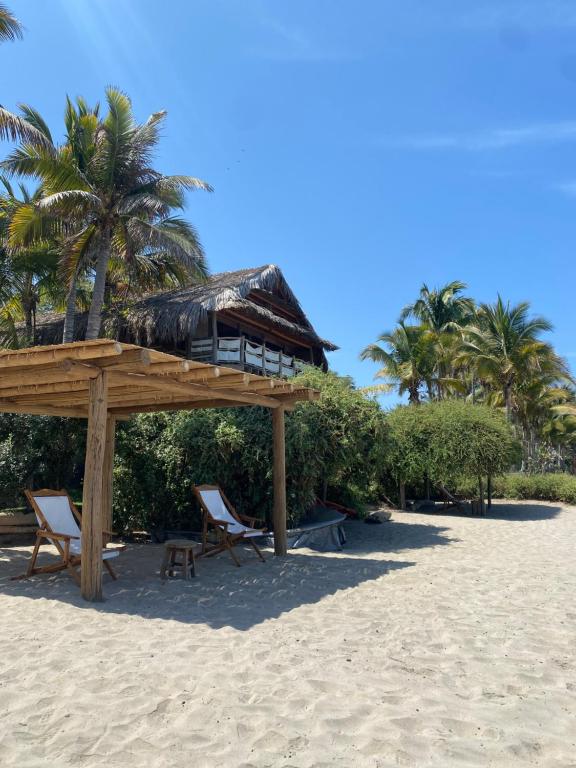 un padiglione sulla spiaggia con sedie e palme di Bungalows Las Balsas a Máncora