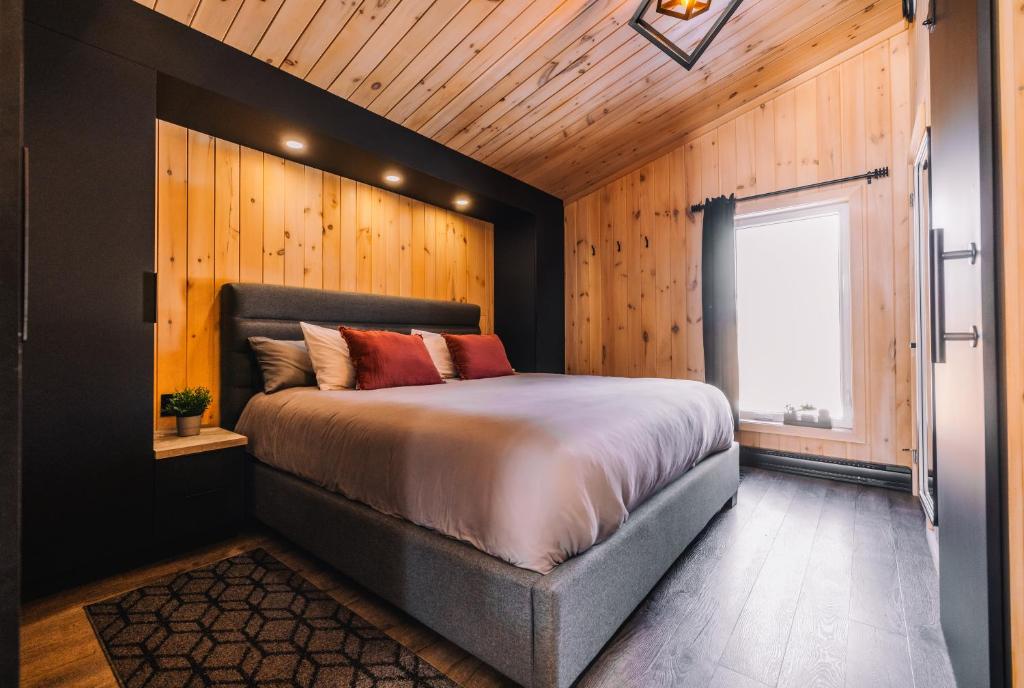 a bedroom with a large bed with a wooden wall at Le Versant Mont-Sainte-Anne in Saint-Férréol-les-Neiges
