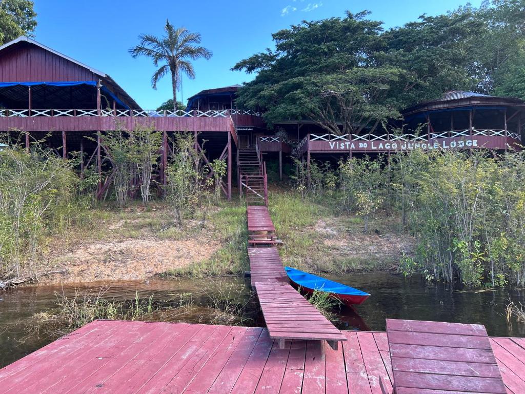 un pont en bois sur une rivière avec un bateau dans l'établissement Vista do Lago Jungle Lodge, à Cajual