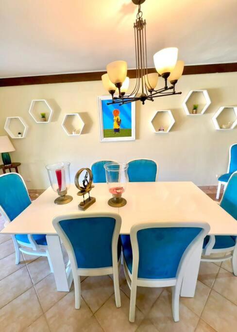 a dining room with a white table and blue chairs at Villa Grupal en Metro Country Club. in La Fe