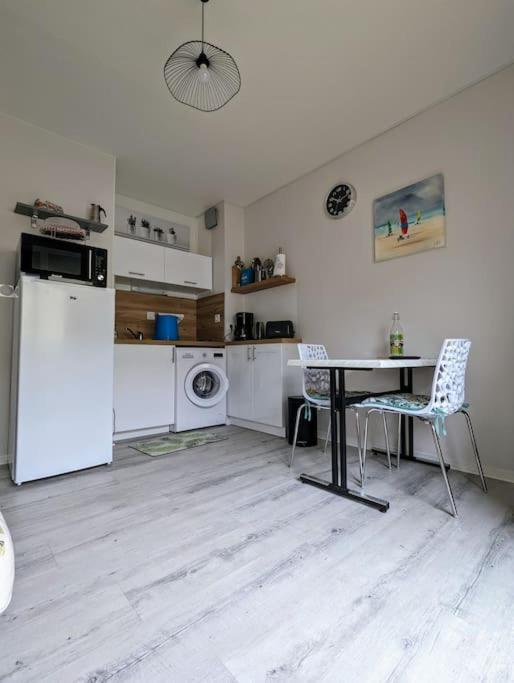 Il comprend une cuisine équipée d'une table, d'un réfrigérateur, d'une table et de chaises. dans l'établissement Appartement à 300m des thermes, à Cazaubon