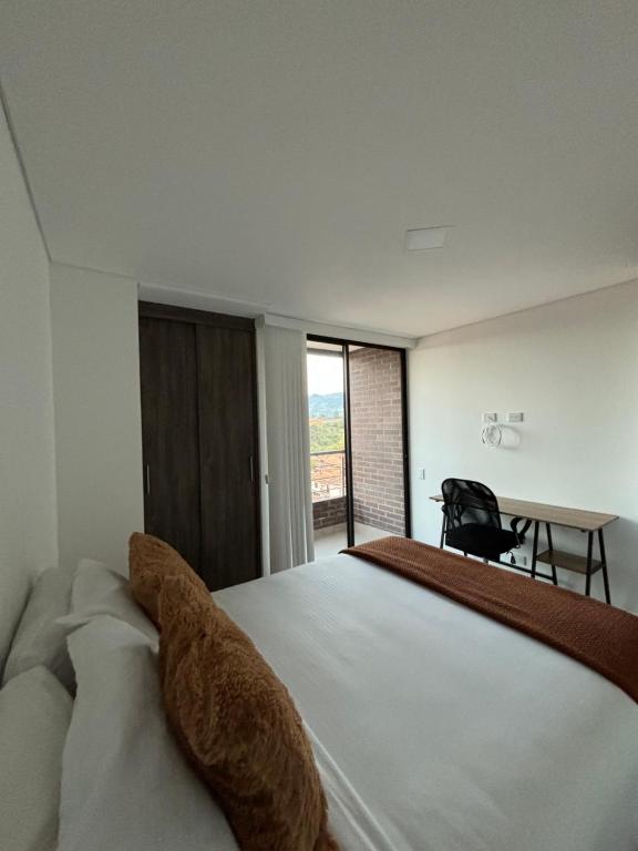 a bedroom with a large white bed and a desk at Alojamiento en El Carmen de Viboral in Carmen de Viboral