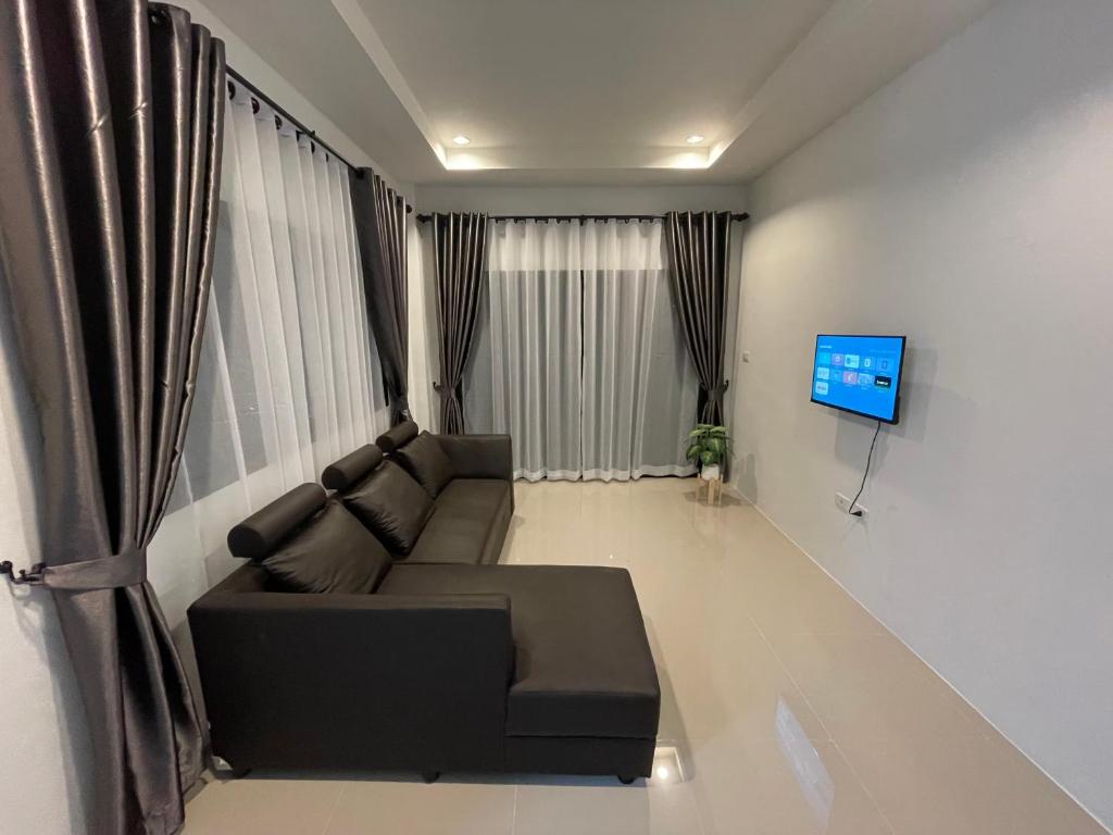 a living room with a couch and a television at บ้านพูลทรัพย์วิลเลจ POONSUB VILLAGe in Ban Na Charoen