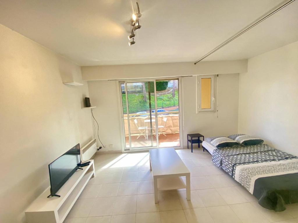 un salon avec un canapé et une télévision dans l'établissement F1 Nice Ouest, Terrasse vue mer, Wifi, à Nice