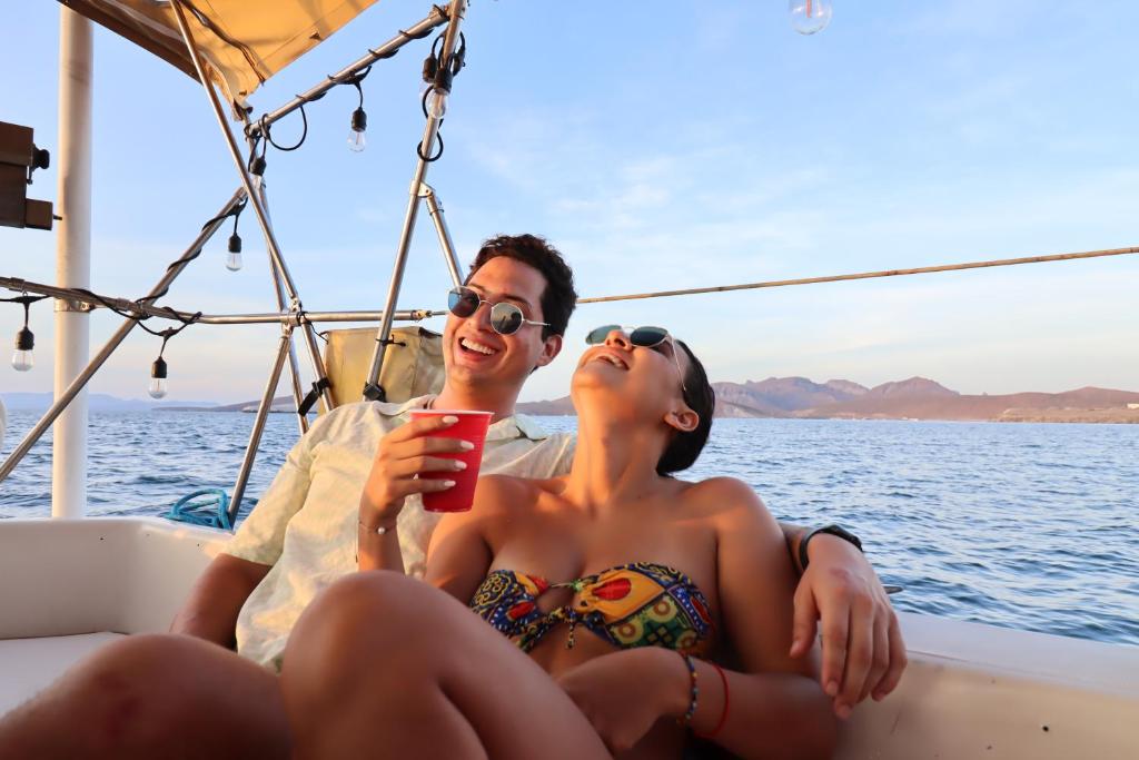 a man and woman in bathing suits sitting on a boat at Duerme en un hermoso Velero dentro de la Marina in La Paz