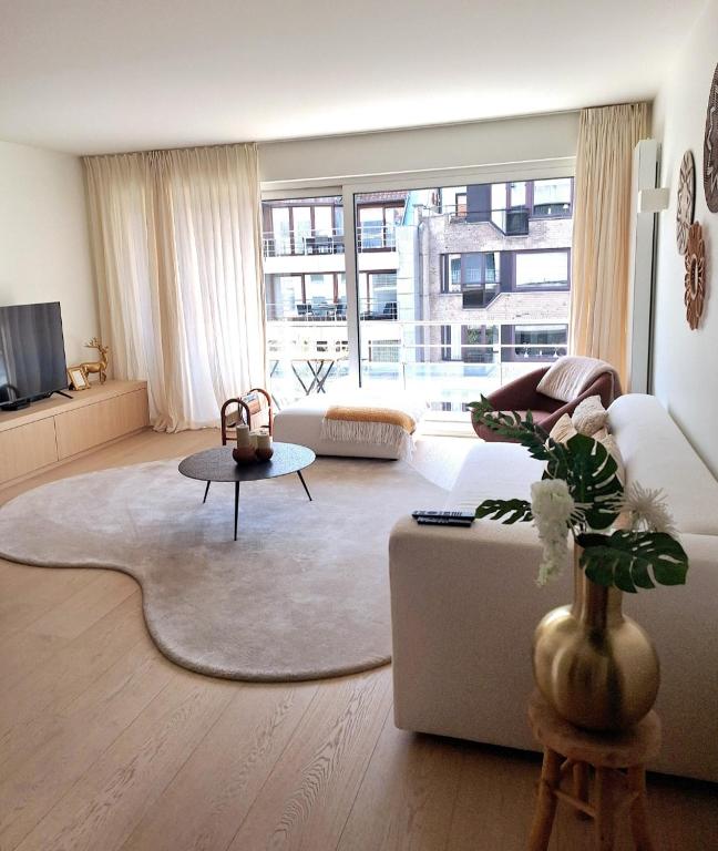 a living room with a white couch and a large window at Appartement Wellington D3 Knokke full service et parking in Knokke-Heist