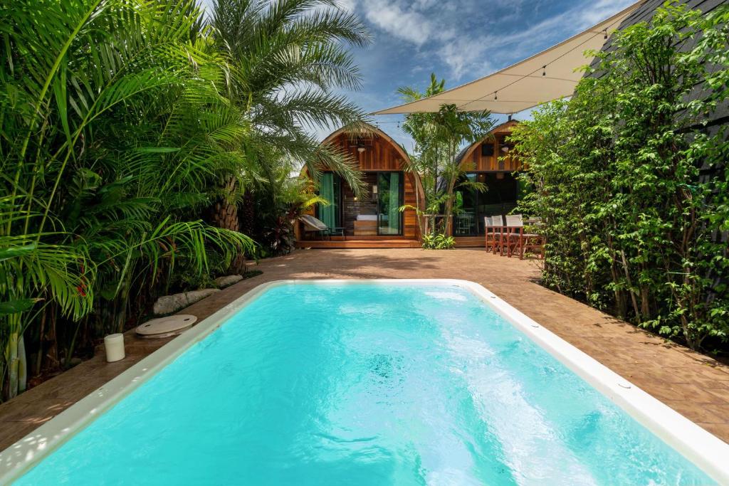 una piscina frente a una casa con árboles en New 3BR Chalet-Style Villa Pasak Paradise 3, Private Pool, 10min grive to Laguna Phuket, en Ban Pak Lak