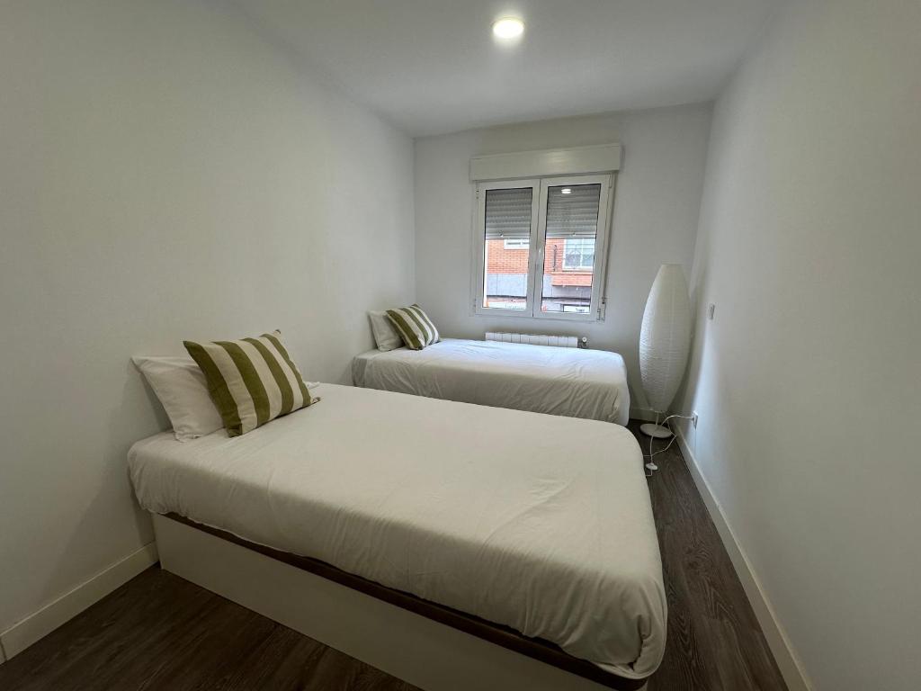 two beds in a small room with a window at Apartamentos dos Habs Madrid Urgel in Madrid
