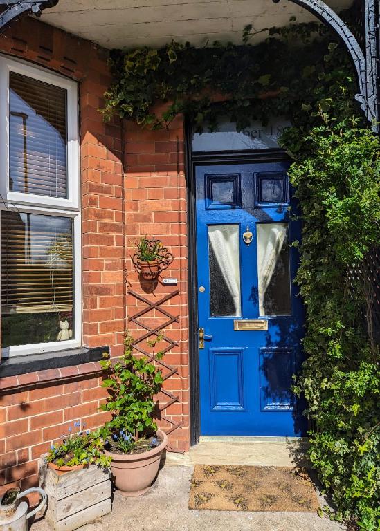 a blue door on a brick house with plants at Number 18 in Whitby