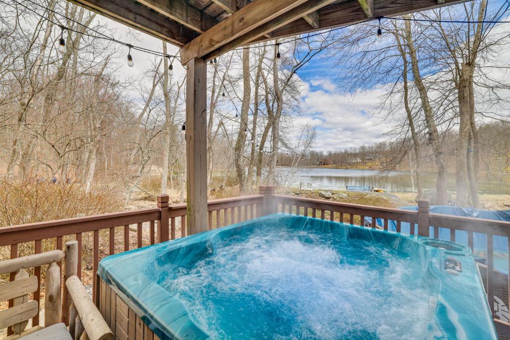 a hot tub on a deck with a view of a lake at East Stroudsburg Home with Private Lake Access, Pool in East Stroudsburg