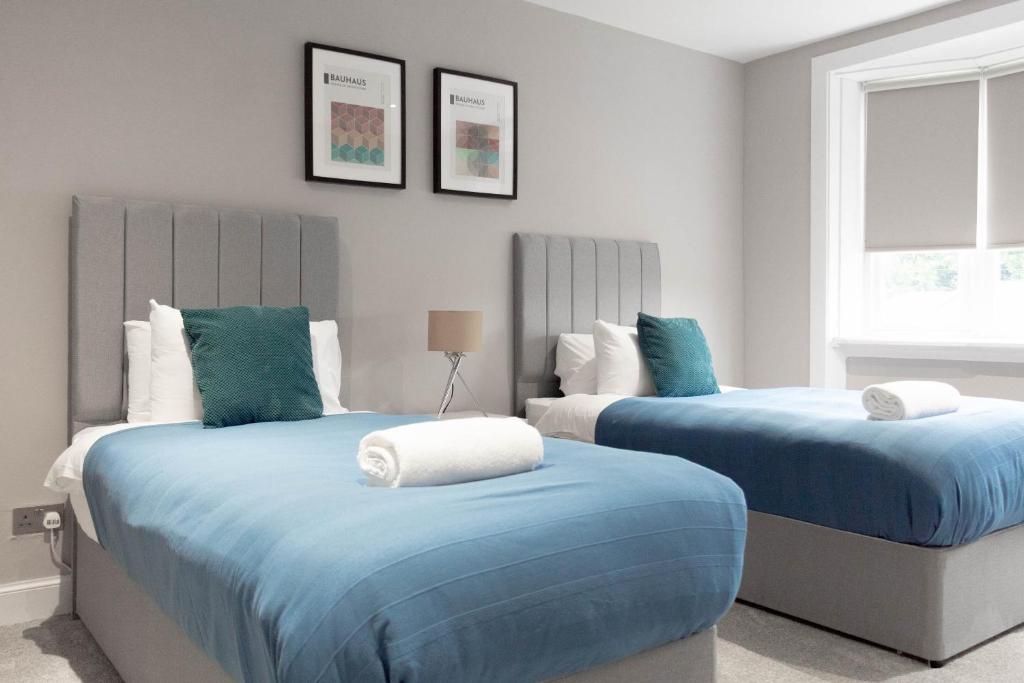two beds in a bedroom with blue and white at Castlemilk House in Glasgow