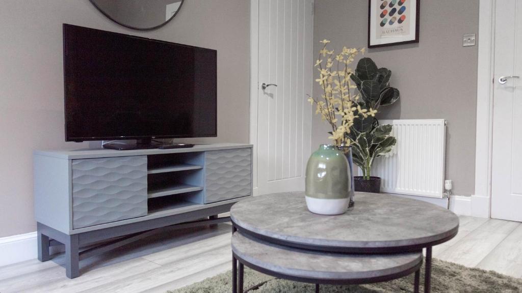 a living room with a tv and a table with a vase at Castlemilk House in Glasgow