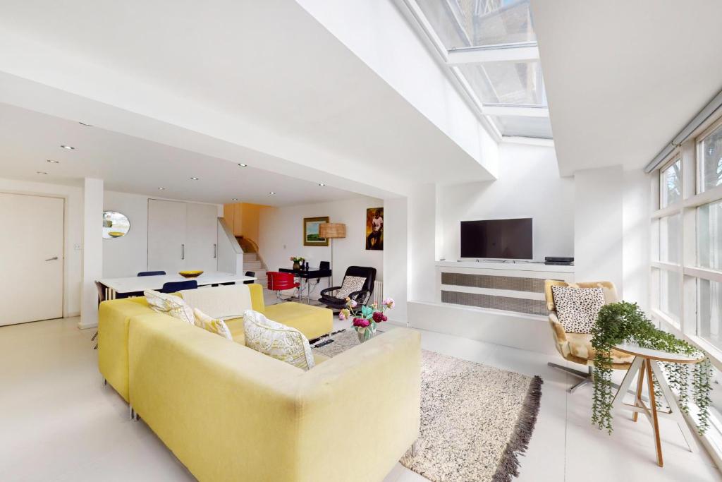 een woonkamer met een gele bank en stoelen bij 1 Bed Maisonette with Garden - 1 min to station Share Save in Londen