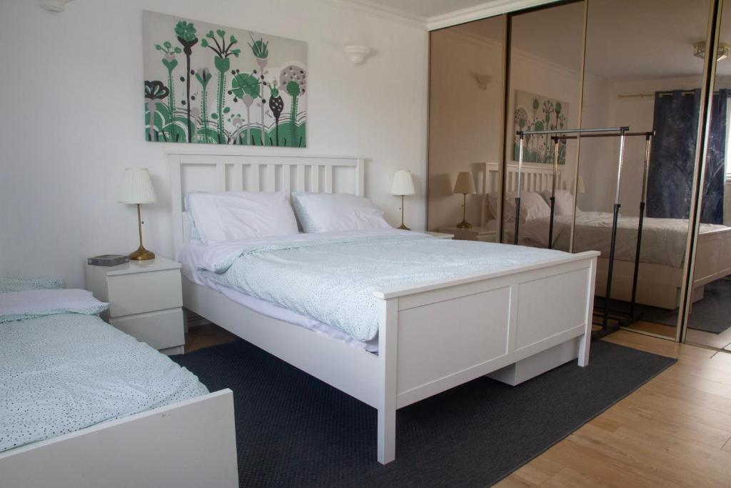 een slaapkamer met een wit bed en een spiegel bij Spacious & bright 4-bedroom town-house with garden in Sydenham