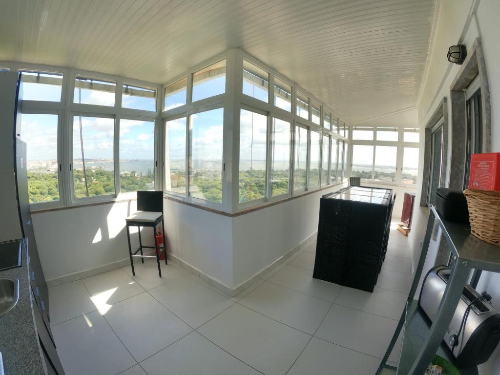 a large room with windows and a table and chairs at Almada apartamento T1 - 1 Renovado, Laranjeiro in Almada