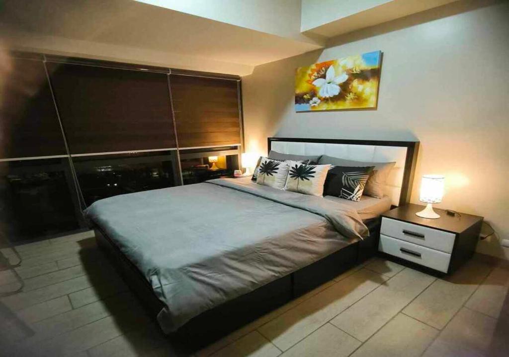- une chambre avec un grand lit et une table avec une lampe dans l'établissement Avery's Place @ One Eastwood Avenue, à Manille