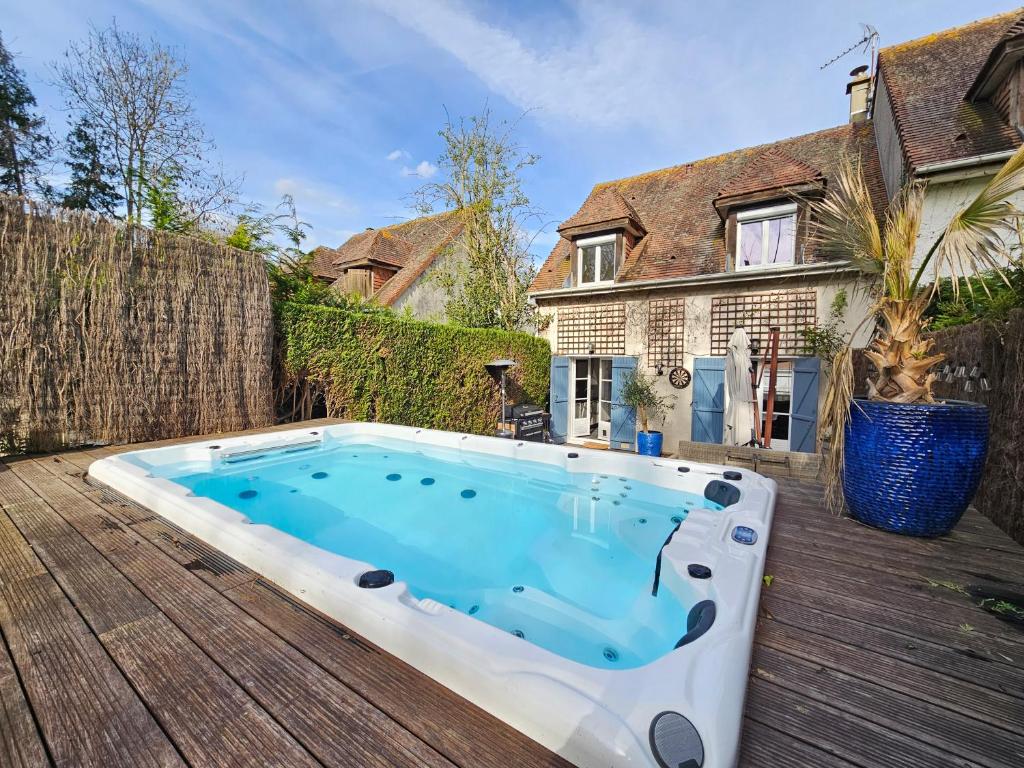 una piscina en una terraza de madera con una casa en Maison familiale 12 couchages, spa et terrasse, en Deauville