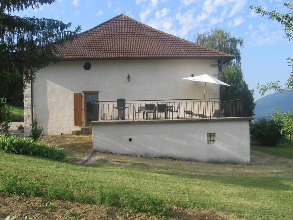 a house with a balcony with a table and an umbrella at la fontaine bénite in Seyssel