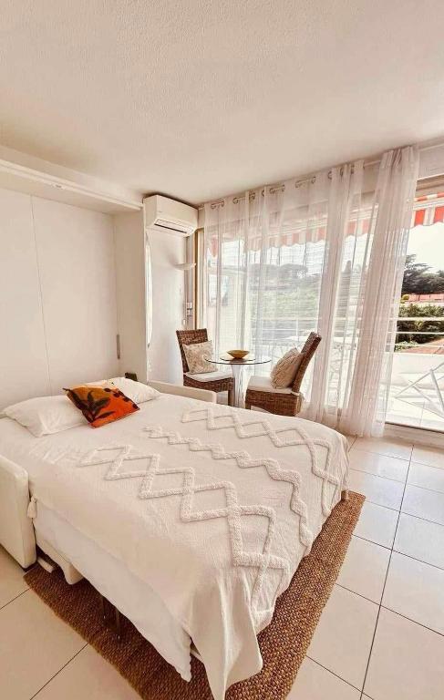 - une chambre avec un lit blanc, une table et des chaises dans l'établissement Eden, à Saint-Tropez
