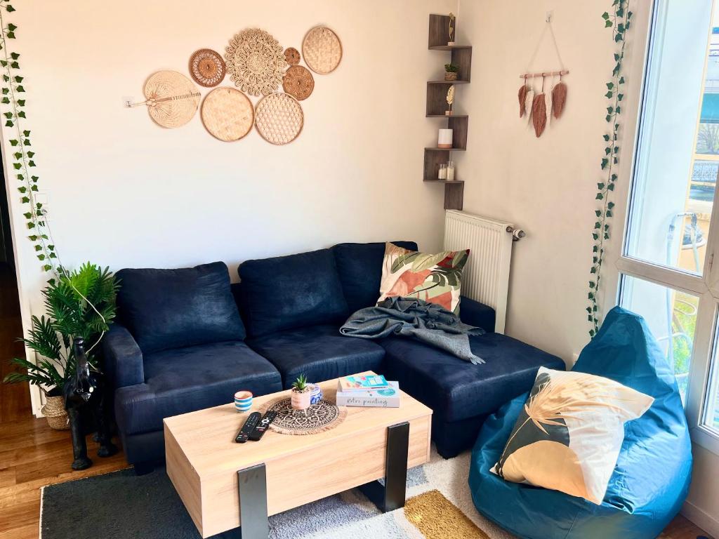 ein Wohnzimmer mit einem blauen Sofa und einem Couchtisch in der Unterkunft Cozy nest 10mn from Stade de France in Aubervilliers